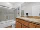 Bright bathroom featuring granite countertops, framed mirror, and bathtub with glass doors at 2452 W Muirfield Dr, Anthem, AZ 85086