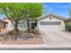 Charming single-story home with desert landscaping, mature tree, and two-car garage at 2452 W Muirfield Dr, Anthem, AZ 85086