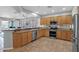 Open kitchen with stainless appliances, wooden cabinets, granite countertops, and tile flooring at 2452 W Muirfield Dr, Anthem, AZ 85086