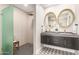 Stylish bathroom featuring dual sinks, gold round mirrors, a floating vanity, and a walk-in shower with a glass partition at 2517 E Sahuaro Dr, Phoenix, AZ 85028