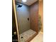 Walk-in shower featuring modern fixtures, stone floor and brown textured ceramic tile in this beautifully remodeled bathroom at 2517 E Sahuaro Dr, Phoenix, AZ 85028