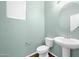 Powder room featuring pedestal sink, round mirror, and toilet with wood-look flooring and fresh paint at 2534 N 73Rd Dr, Phoenix, AZ 85035