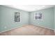 Bright bedroom featuring neutral carpet, two windows with blinds, and light green colored walls at 2534 N 73Rd Dr, Phoenix, AZ 85035