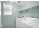 Well-lit laundry room featuring a modern washer and dryer, neutral colored walls, and upper shelf for storage at 2534 N 73Rd Dr, Phoenix, AZ 85035