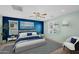 Staged bedroom with blue accent wall, plush bedding, a ceiling fan, and natural light from two windows at 2534 N 73Rd Dr, Phoenix, AZ 85035