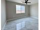 Bright bedroom features sleek, gray tile flooring, ceiling fan, and a window offering outdoor views at 25745 W Peak View Rd, Wittmann, AZ 85361