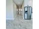 Inviting hallway featuring stylish marble tile flooring, leading to a bright, welcoming entrance door and stainless steel refrigerator at 25745 W Peak View Rd, Wittmann, AZ 85361