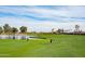 Golf course with players, pond and clear blue sky at the luxurious community at 2722 N 155Th Dr, Goodyear, AZ 85395