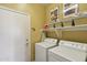 Convenient laundry room featuring a side-by-side washer and dryer, storage shelf and door to outside at 2722 N 155Th Dr, Goodyear, AZ 85395