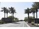 Elegant community entrance with palm tree lined road and signage creating a welcoming atmosphere at 3165 N 306Th Ln, Buckeye, AZ 85396