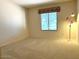 Carpeted bedroom featuring a lamp and window with blinds at 3242 W Christy Dr, Phoenix, AZ 85029
