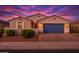 Charming single-story home featuring a blue garage door, desert landscaping, and a colorful sunset backdrop at 4140 E Caitlin Dr, San Tan Valley, AZ 85140