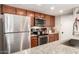 Well-equipped kitchen featuring a stainless steel refrigerator, granite counters, and wooden cabinets at 4305 E Cherokee St, Phoenix, AZ 85044