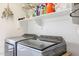 Functional laundry room equipped with modern washer and dryer, storage shelves, and ample space for sorting and folding at 4423 W Escuda Dr, Glendale, AZ 85308