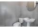 Compact half bath showcases a modern pedestal sink, toilet, and neutral gray wall color at 7336 S 48Th Gln, Laveen, AZ 85339