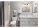 Well-lit bathroom with a white vanity, decorative mirror, gray walls, and a shower with a gray curtain at 8229 E Farmdale Dr, Mesa, AZ 85208