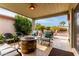 Inviting covered patio with seating around a stone fire pit, plants, and beautiful desert landscaping at 8229 E Farmdale Dr, Mesa, AZ 85208