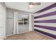Bedroom with a ceiling fan, purple striped accent wall and neutral color carpet at 11321 W Austin Thomas Dr, Surprise, AZ 85378