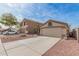 View of beige homes with two-car garages, desert landscaping, and concrete driveways at 11321 W Austin Thomas Dr, Surprise, AZ 85378