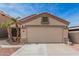 Beige, single-story home featuring a two-car garage, desert landscaping, and a tiled roof against a clear, sunny sky at 11321 W Austin Thomas Dr, Surprise, AZ 85378