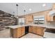 Bright kitchen with light wood cabinets, black appliances, peninsula and a modern accent wall in the dining area at 11321 W Austin Thomas Dr, Surprise, AZ 85378
