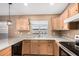 Kitchen featuring light wood cabinets, light countertops, black appliances, and a stainless steel sink with window at 11321 W Austin Thomas Dr, Surprise, AZ 85378