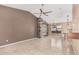 View of a spacious living room with modern ceiling fan, tile flooring, and adjacent kitchen space at 11321 W Austin Thomas Dr, Surprise, AZ 85378