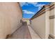 A stone lined side yard between two stucco walls with a metal gate at the end at 11321 W Austin Thomas Dr, Surprise, AZ 85378