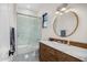Bright bathroom features a shower-over-tub with glass doors and a vanity with a round mirror at 12633 N 81St St, Scottsdale, AZ 85260