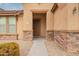 Inviting front entrance with a wood door and stone veneer accents, enhanced by desert landscaping at 18374 W Stinson Dr, Surprise, AZ 85374