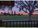 Backyard view from porch featuring beautiful lush lawn and colorful sunset beyond the treeline at 18607 N 125Th Ave, Sun City West, AZ 85375