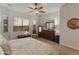 Bright bedroom with ceiling fan, large window and sunset view, dresser, and decorative accents at 20289 N 259Th Ave, Buckeye, AZ 85396