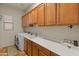Bright laundry room features wooden cabinets, white countertops, sink, and modern washer and dryer at 20289 N 259Th Ave, Buckeye, AZ 85396