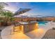 Outdoor kitchen with a built-in barbecue, prep area, and bar seating overlooking the pool at 20289 N 259Th Ave, Buckeye, AZ 85396