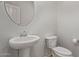 Modern powder room with pedestal sink, round mirror, and neutral color scheme at 23728 W Magnolia Dr, Buckeye, AZ 85326