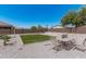 Backyard features gravel landscaping, artificial grass, mature trees, and a dining set at 2377 S 245Th Dr, Buckeye, AZ 85326