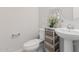 Half bath featuring a pedestal sink, toilet, and stylish storage shelves adorned with elegant decorations at 2377 S 245Th Dr, Buckeye, AZ 85326
