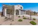 View of the property, featuring a two car garage door, an arched entry, and minimal desert landscaping at 2377 S 245Th Dr, Buckeye, AZ 85326
