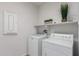 Clean laundry room with modern washer and dryer units and ample shelving space at 2377 S 245Th Dr, Buckeye, AZ 85326
