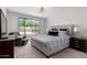 The main bedroom featuring a large window overlooking the private backyard, a gray upholstered bed frame, and soft carpet at 2377 S 245Th Dr, Buckeye, AZ 85326