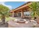Covered patio with a gas fire pit, chairs, ceiling fans, lush landscaping, and turf area in this backyard at 27926 N 130Th Ave, Peoria, AZ 85383
