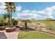 A gas firepit surrounded by synthetic grass and palm trees overlooking a golf course creates a relaxing outdoor space at 27926 N 130Th Ave, Peoria, AZ 85383