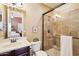 Neutral tiled bathroom with framed glass shower, single sink vanity and view into main bedroom at 27926 N 130Th Ave, Peoria, AZ 85383