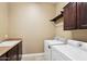 Bright laundry room features utility sink, washer, dryer and upper storage cabinet at 27926 N 130Th Ave, Peoria, AZ 85383