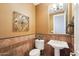 Elegant powder room with decorative tile wainscoting, pedestal sink, and decorative wall art at 27926 N 130Th Ave, Peoria, AZ 85383