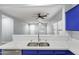 Contemporary kitchen with a double sink, white countertops, blue cabinets, and a seamless view to the living room at 40054 W Tamara Ln, Maricopa, AZ 85138