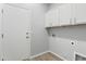 Well-lit laundry room features sleek wood flooring and ample overhead storage, complete with utility hookups and access door at 40054 W Tamara Ln, Maricopa, AZ 85138
