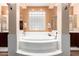 Bright bathroom with a luxurious soaking tub surrounded by white tile and a glass block window at 4125 W Lydia Ln, Phoenix, AZ 85041