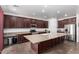 A kitchen features wood cabinets, stainless steel appliances, a large granite island, and tile flooring at 4125 W Lydia Ln, Phoenix, AZ 85041