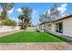 Spacious backyard with gravel perimeter, synthetic lawn, and covered patio, ideal for entertaining at 438 E Hackamore St, Mesa, AZ 85203